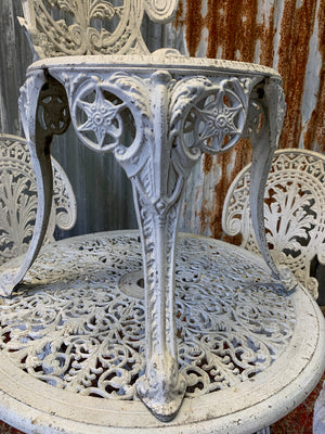 A white cast metal garden table and four chairs