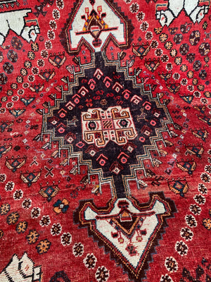 A large red ground rectangular Persian rug with camel motif