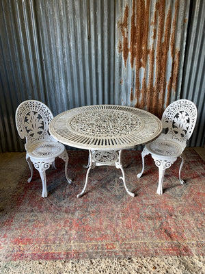 A white cast metal garden set - a large table and two chairs