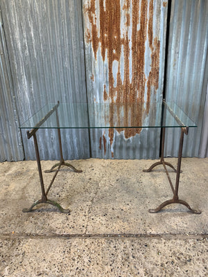 A cast iron trestle base dining table with glass top