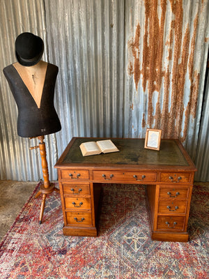 A mahogany pedestal desk with green leather top