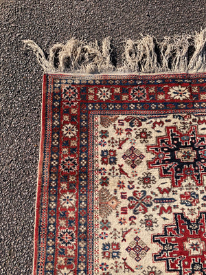 A cream ground Persian rectangular rug with long fringe- 260cm x 134cm