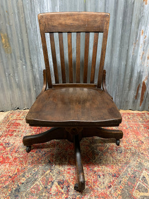 A wooden banker's swivel desk chair