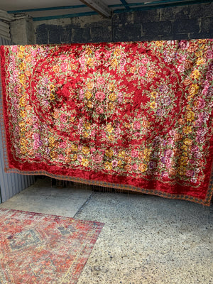 A large red velvet throw with floral decoration