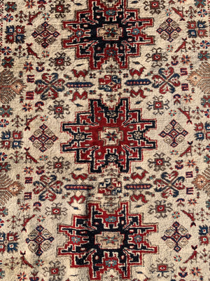 A cream ground Persian rectangular rug with long fringe- 260cm x 134cm