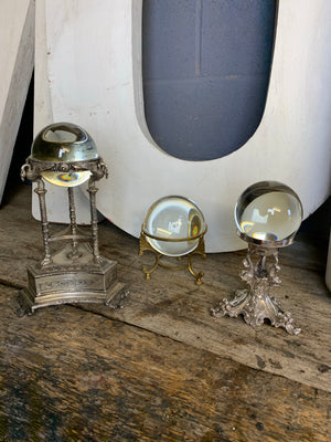 A large fortune teller's crystal ball on a brass tripod base