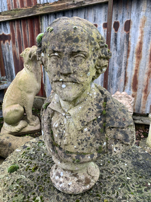 A weathered cast stone bust of Shakespeare on a pedestal column