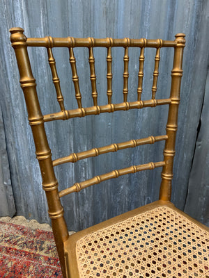 A set of four faux bamboo chairs with cane seats