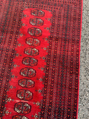 A Persian red ground rectangular Bokhara rug