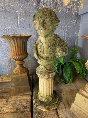 A weathered cast stone bust of Shakespeare on a pedestal column