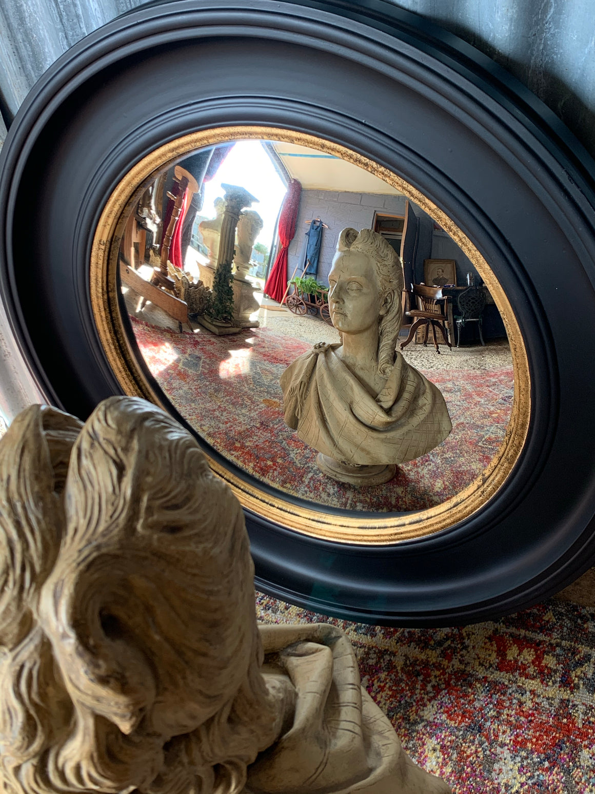 A large black and gold convex mirror