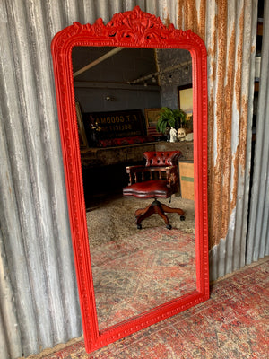 A large red floor standing mirror