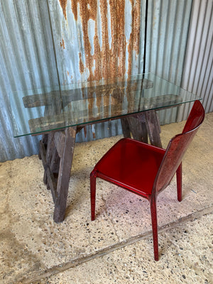 A wooden trestle base table with glass top