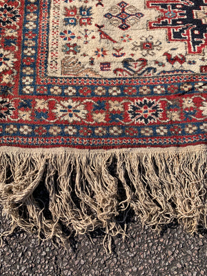 A cream ground Persian rectangular rug with long fringe- 260cm x 134cm