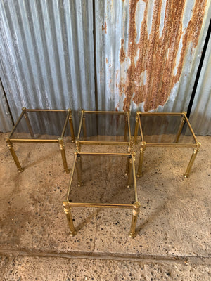 A set of four metamorphic square Hollywood Regency stacking side tables with smoked glass