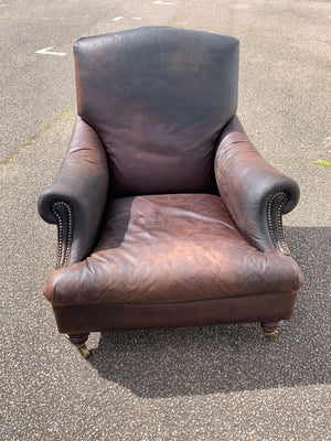 A deep leather armchair raised on castors