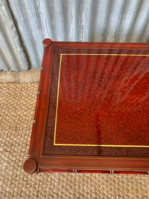 A red faux bamboo side table with glass top
