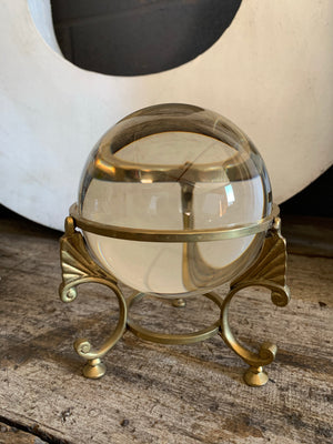 A large fortune teller's crystal ball on a brass tripod base