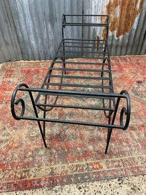 A wrought iron strapwork bench with scrolled arms