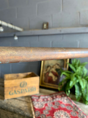 A vintage industrial copper pipe clothing rack