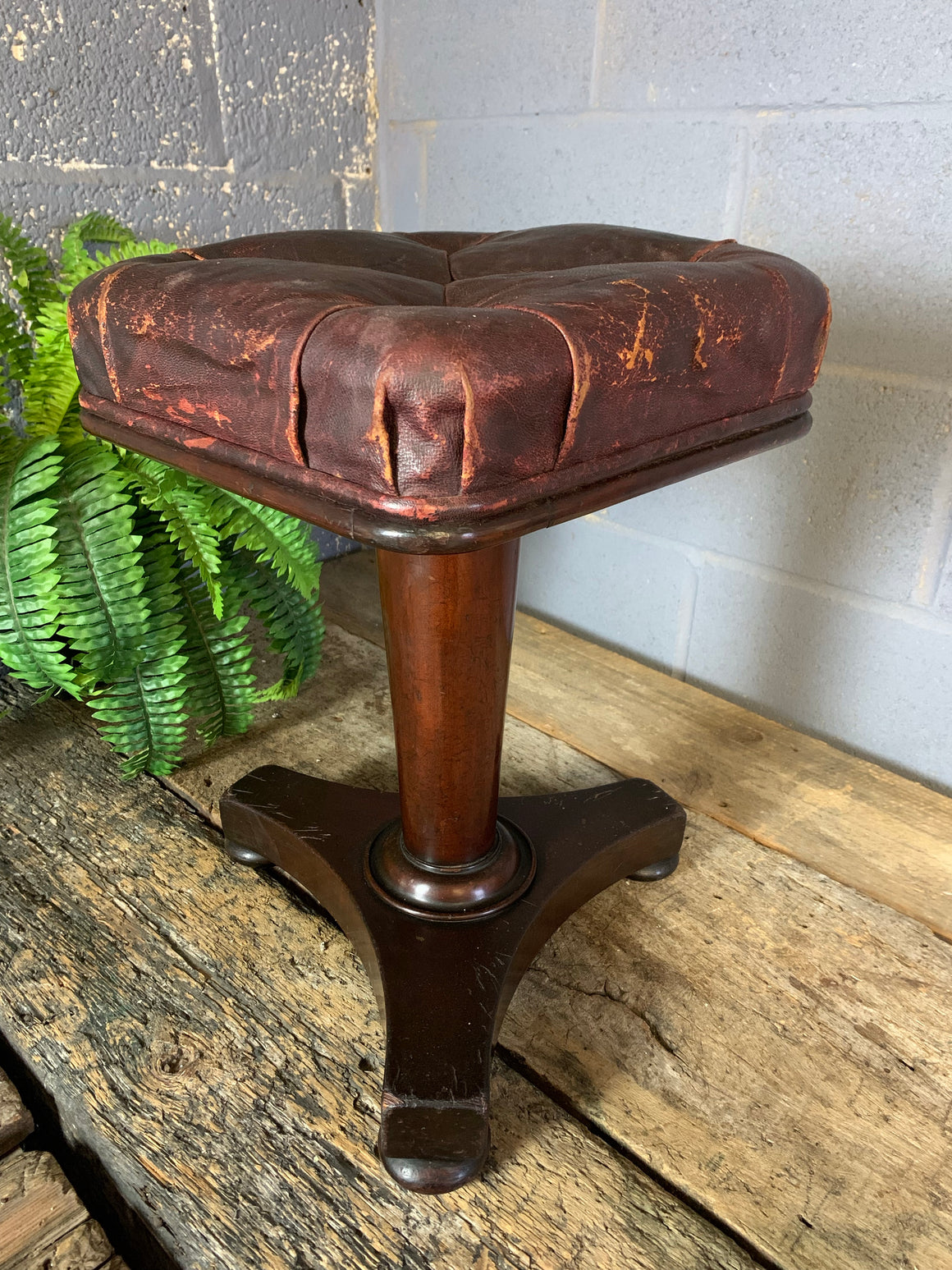 A red leather and mahogany stool