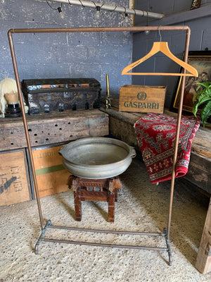 A vintage industrial copper pipe clothing rack