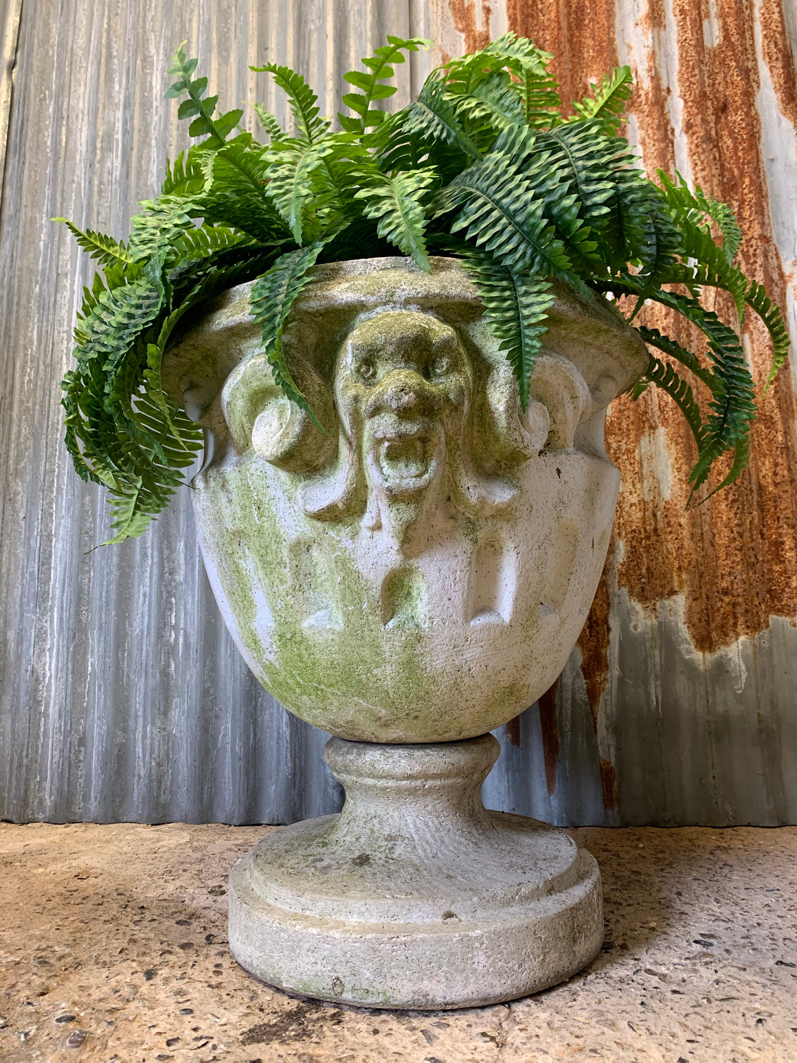 A very large urn with jester head detailing