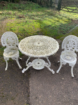 A white cast metal table and two chairs garden set