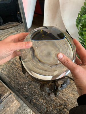 A large fortune teller's crystal ball on a bronze stand