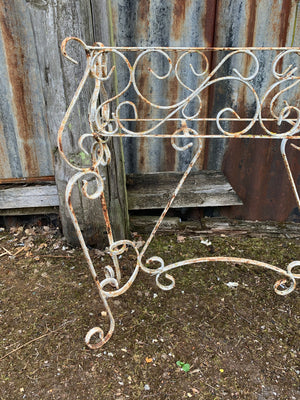 A weathered white wrought iron wirework planter