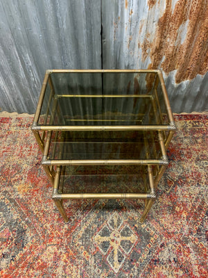 A brass and glass Hollywood Regency nest of faux bamboo tables