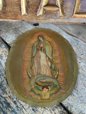 An oval painting on metal of The Madonna of Guadalupe