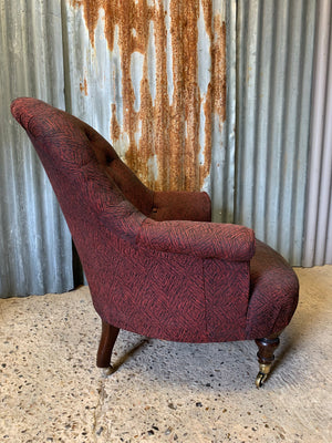 A black and red button back Victorian armchair raised on castors