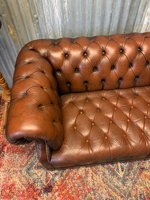 A brown two seater Chesterfield sofa with button back and seat