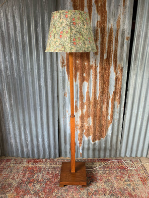 An Art Deco oak standard lamp with a William Morris style shade