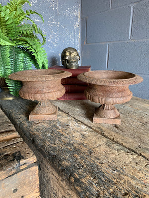 A pair of weathered cast iron urns