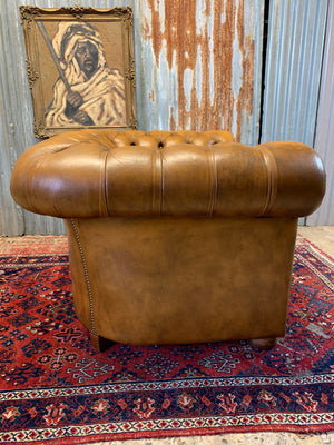 A brown Chesterfield armchair with button back and seat