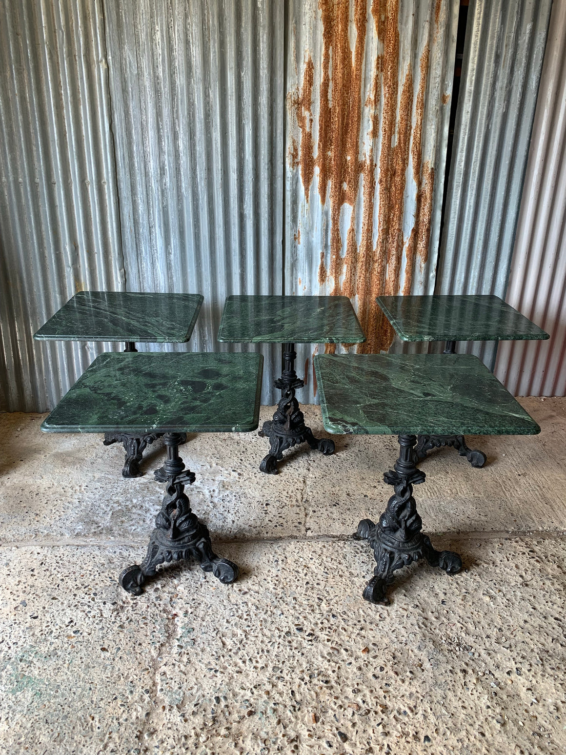 A cast iron dolphin bistro table with Verde Indio green marble top