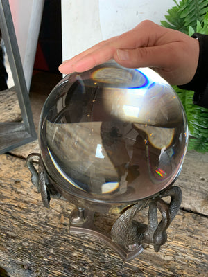 A large fortune teller's crystal ball on a bronze stand