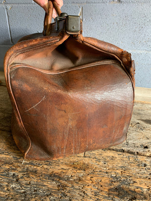 A large brown leather monogrammed Gladstone bag