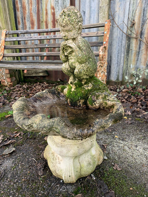 A cast stone birdbath with the figure of a fawn
