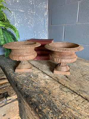 A pair of weathered cast iron urns