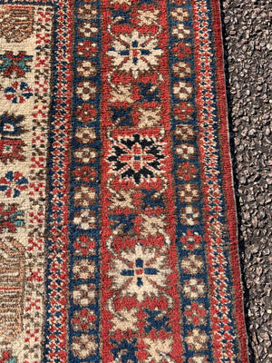 A cream ground Persian rectangular rug with long fringe- 260cm x 134cm