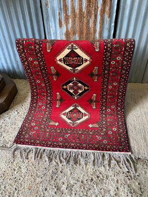 A hand woven Persian red ground rectangular rug
