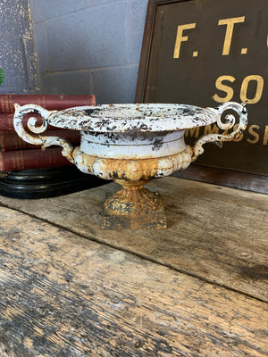 A white cast iron garden urn with twin handles