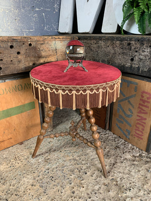 A wooden bobbin gypsy table with red velvet top