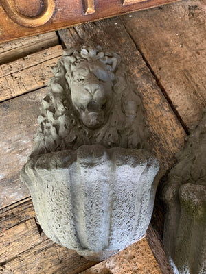 A pair of cast stone lion head wall planters