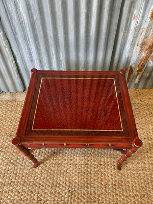 A red faux bamboo side table with glass top
