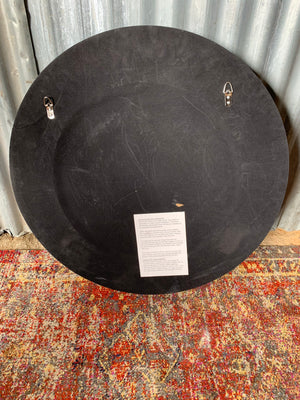 A large black and gold convex mirror