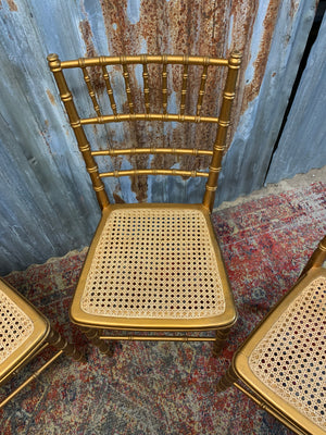 A set of four faux bamboo chairs with cane seats